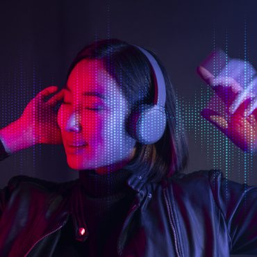 Woman listening to music with wireless headphones beside a laptop