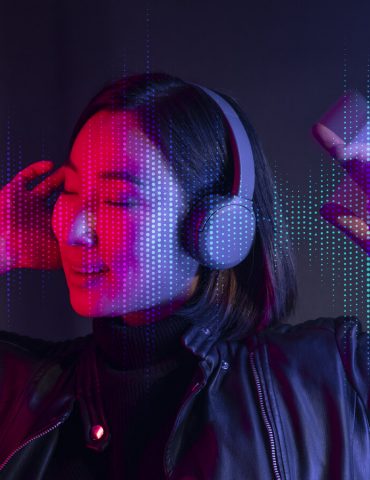 Woman listening to music with wireless headphones beside a laptop