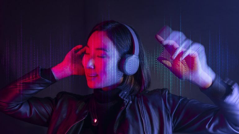 Woman listening to music with wireless headphones beside a laptop
